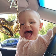 élia participe au concours pour gagner de l'argent avec cette photo : baby, blurred_background, car_interior, charm, child, cute, happy, heart_shaped, outdoor, pendant, person, pink_sweater, playful, rearview_mirror, seat, smiling, steering_wheel, tongue_out, window, young_child