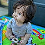 baby, blue_eyes, child, close_up, colorful, curious, cute, dark_hair, feet, hands, infant, messy_shirt, outdoor, play_mat, portrait, red_car, sitting, toddler, toy, wooden_toy