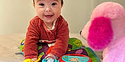 Amélie participe au concours pour gagner de l'argent avec cette photo : baby, child, toy, play_mat, stuffed_animal, pink, colorful, smile, indoor, happy, infant, person, cute, soft_toy, bed, clothing, face, eyes, hands, toddler