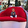 Ewenn a rejoint le concours — aidez-le/la à gagner de superbes lots ! child, christmas_trees, clothing, cute, face, festive, happy, holiday_decorations, indoor, jeans, lights, portrait, red_chair, seasonal, shopping_mall, sitting, striped_shirt, toddler, white_shoes, winter