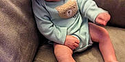 Sammy is registered to the contest to win money with this photo: baby, cap, child, couch, cute, dinosaur_print, face, foot, furniture, hand, indoor, infant, legs, onesie, portrait, relaxed, seated, skin, smiling, teddy_bear_patch