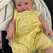 Braelynn joined the competition — help win amazing prizes! baby, infant, yellow_clothing, romper, blanket, smiling, face, skin, arm, hand, sitting, cozy, cute, child, portrait, indoors, soft_texture, happy, eyes, rosy_cheeks