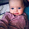 Braelynn is registered to the contest to win money with this photo: baby, child, face, blue_eyes, onesie, purple_clothing, polka_dots, smile, indoor, bed, blanket, portrait, cute, infant, young_child, cozy, warm_clothing, person, closeup, soft_lighting