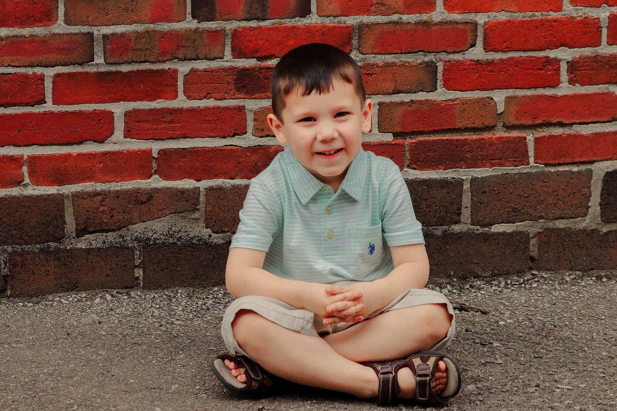 Kenzie James is registered to the contest to win money with this photo: baby_toddler_clothing, brick, brickwork, child, chin, facial_expression, flooring, footwear, fun, happy, human_leg, joy, knee, pattern, person, photograph, shorts, sitting, sleeve, smile