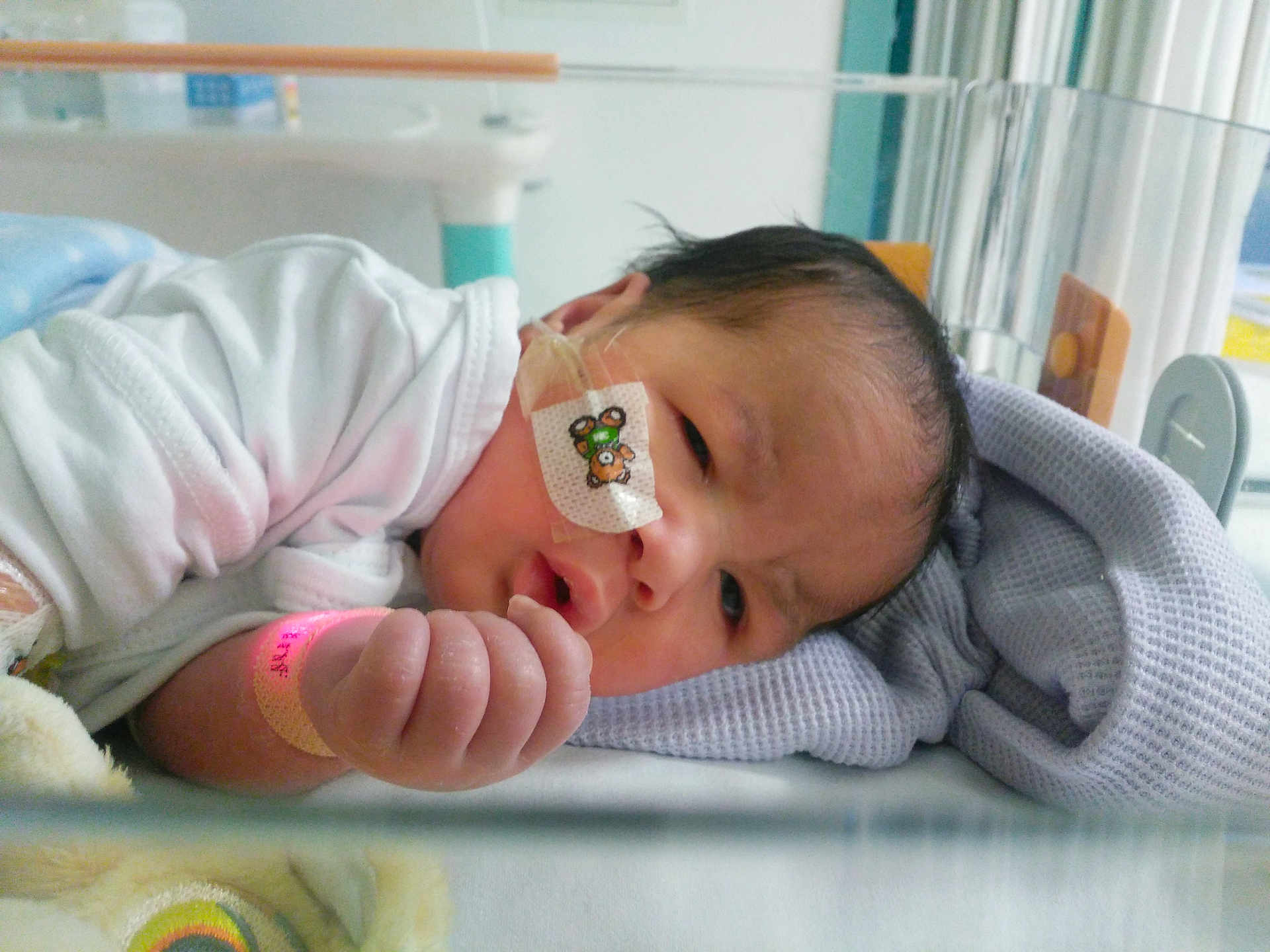 Leo joined the competition — help win amazing prizes! baby, infant, hospital, crib, blanket, medical_tape, nasal_tube, wristband, white_clothing, face, hand, bed, soft_toy, healthcare, newborn, indoors, patient, person, resting, cute