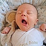 animal_print, baby, blanket, child, cozy, cushion, cute, face, hand, indoors, infant, newborn, onesie, patterned, resting, sleepy, soft_fabric, soft_toy, wrapped, yawning