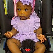 Jailee is registered to the contest to win money with this photo: baby, child, car_seat, purple_outfit, headband, flower, white_socks, frilly_socks, black_car_seat, infant, cute, portrait, seated, looking_away, indoors, adorable, clothing, person, young_child, expression