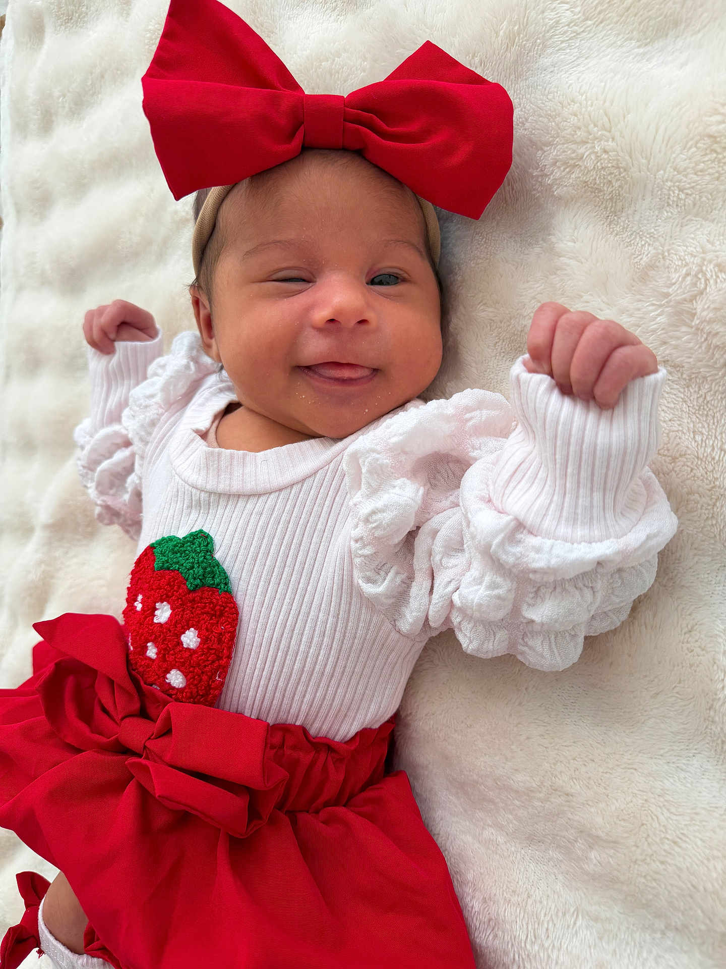 Théliance participe au concours pour gagner de l'argent avec cette photo : baby, infant, newborn, bow, red_bow, headband, winking, tongue_out, smiling, white_blanket, cozy_blanket, red_skirt, strawberry_patch, ruffled_sleeves, lying_down, closeup, tiny_hands, soft_texture, portrait, cute
