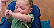 Zaylen is registered to the contest to win money with this photo: baby, child, clothing, cute, fingers, green_onesie, hand, indoor, infant, lap, newborn, pacifier, peaceful, person, portrait, relaxation, resting, seated, skin, sleeping