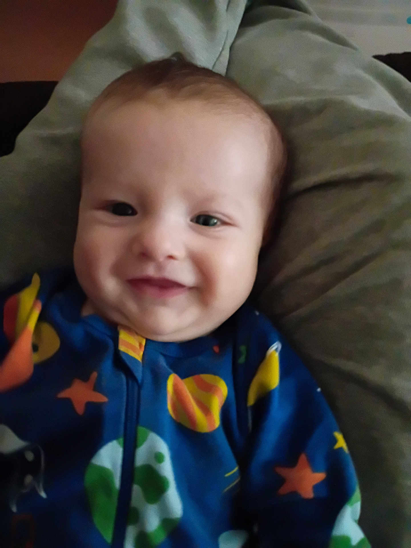 Lucifer joined the competition — help win amazing prizes! baby, infant, smiling, face, onesie, blue_onesie, stars_pattern, planets_pattern, cozy, pillow, blanket, portrait, closeup, cheeks, happy, child, indoor, reclining, newborn, fabric