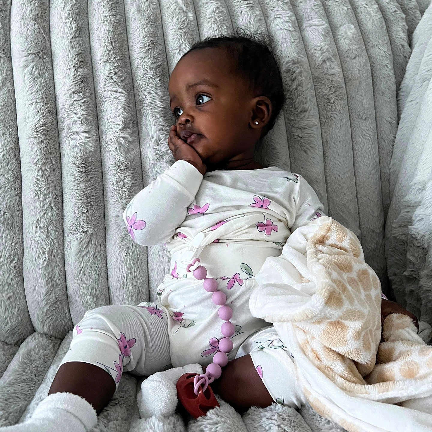 Khloé is registered to the contest to win money with this photo: baby, blanket, child, comfort, couch, cozy, cute, giraffe_pattern, indoor, pacifier_clip, pajamas, person, plush_couch, relaxed, resting, seated, socks, soft_texture, thoughtful, toddler