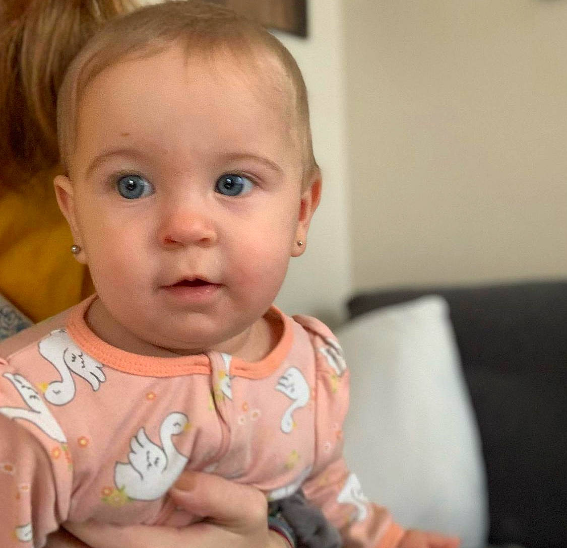 Eleanor is registered to the contest to win money with this photo: arm, baby, baby_toddler_clothing, cheek, chin, dress, ear, eyelash, finger, gesture, hair, hand, happy, iris, lip, mouth, nose, person, skin, sleeve