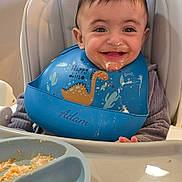 Adam joined the competition — help win amazing prizes! baby, bib, child, clothing, cute, dinosaur, face, feeding, food, happy, high_chair, indoor, infant, meal, messy, person, plate, smiling, tongue_out, young