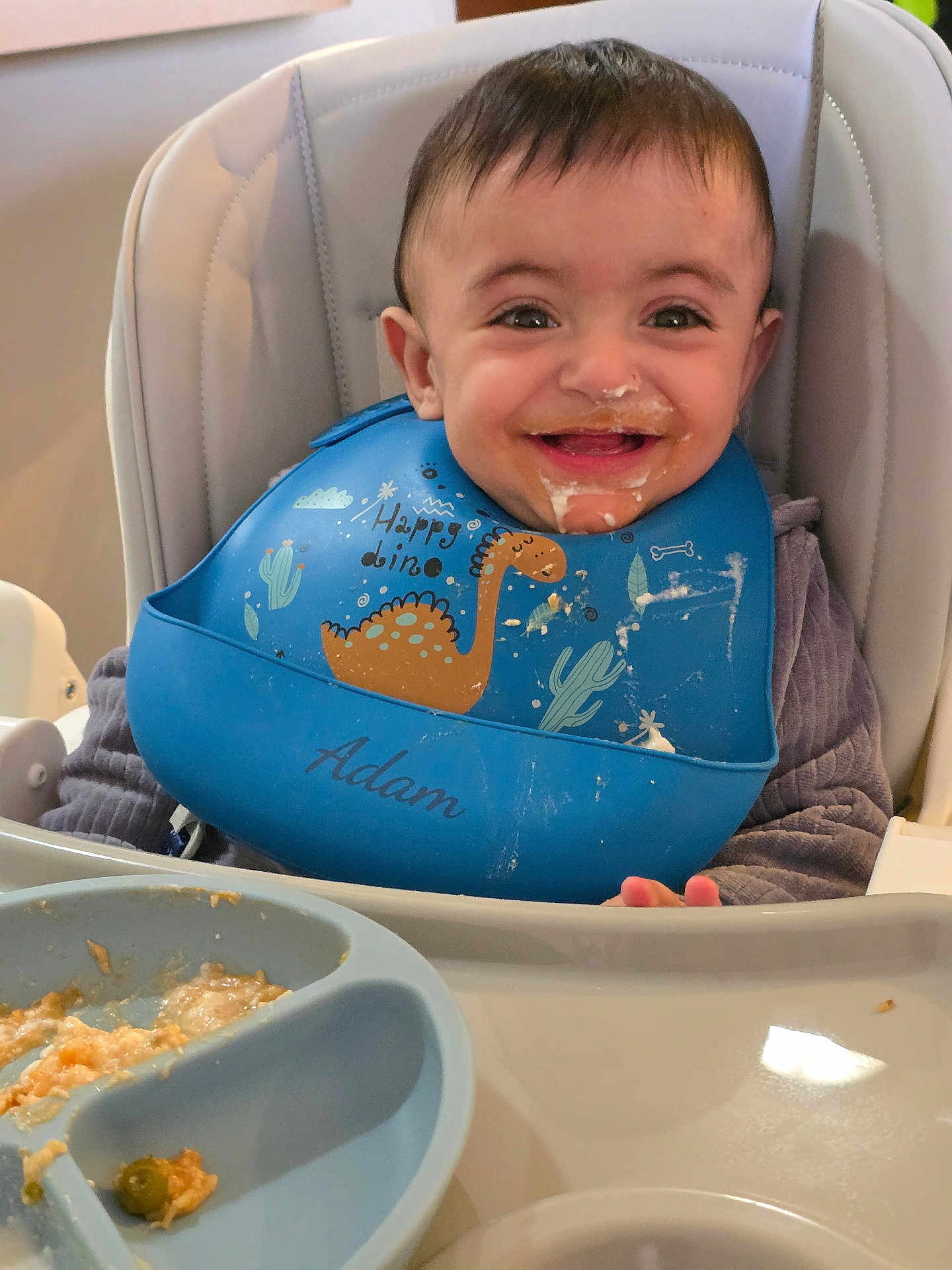 Adam joined the competition — help win amazing prizes! baby, bib, child, clothing, cute, dinosaur, face, feeding, food, happy, high_chair, indoor, infant, meal, messy, person, plate, smiling, tongue_out, young