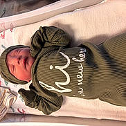 Keoni is registered to the contest to win money with this photo: newborn, baby, sleeping, infant, crib, blanket, clothing, hood, onesie, green, striped, nursery, bed, portrait, resting, peaceful, face, closed_eyes, textile, indoors