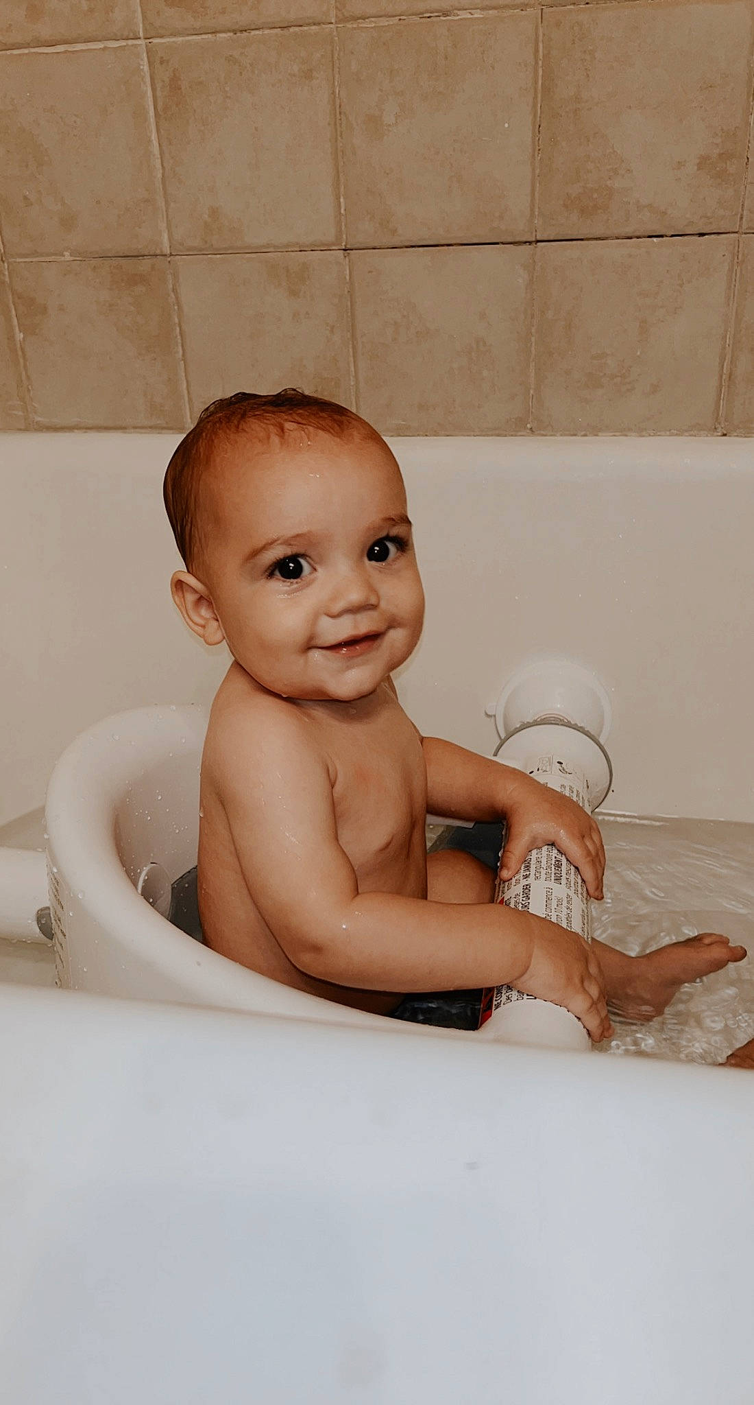 Eli is registered to the contest to win money with this photo: baby, baby_bathing, barefoot, bathing, bathroom, bathtub, chest, child, flooring, fluid, foot, fun, happy, human_leg, joy, person, plumbing, plumbing_fixture, smile, stomach