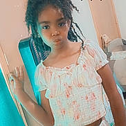 Thea is registered to the contest to win money with this photo: child, girl, indoor, pose, peace_sign, black_heart_emoji, floral_clothing, two_piece_outfit, door, chair, expression, pout, hair, curly_hair, window, tissue_box, casual, young_person, standing, room