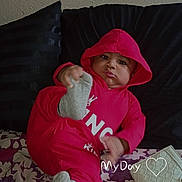 Lakendrick Jr. is registered to the contest to win money with this photo: baby, child, hoodie, red_clothing, sock, foot, pillow, cushion, blanket, floral_pattern, purse, indoor, person, cute, playful, portrait, sitting, expression, wall, fabric