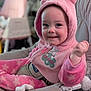 baby, child, pink_clothing, onesie, hood, bear_ears, smile, face, infant, sitting, baby_chair, indoor, cute, happy, fist, soft_texture, cozy, apparel, young_child, plush