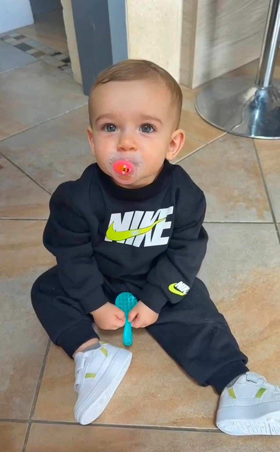 Heyden a rejoint le concours — aidez-le/la à gagner de superbes lots ! toddler, child, pacifier, black_clothing, nike_logo, sitting, indoor, tile_floor, white_shoes, blue_brush, curious_eyes, short_hair, casual, flooring, metal_chair_base, cute, young_child, fashion, comfort, baby