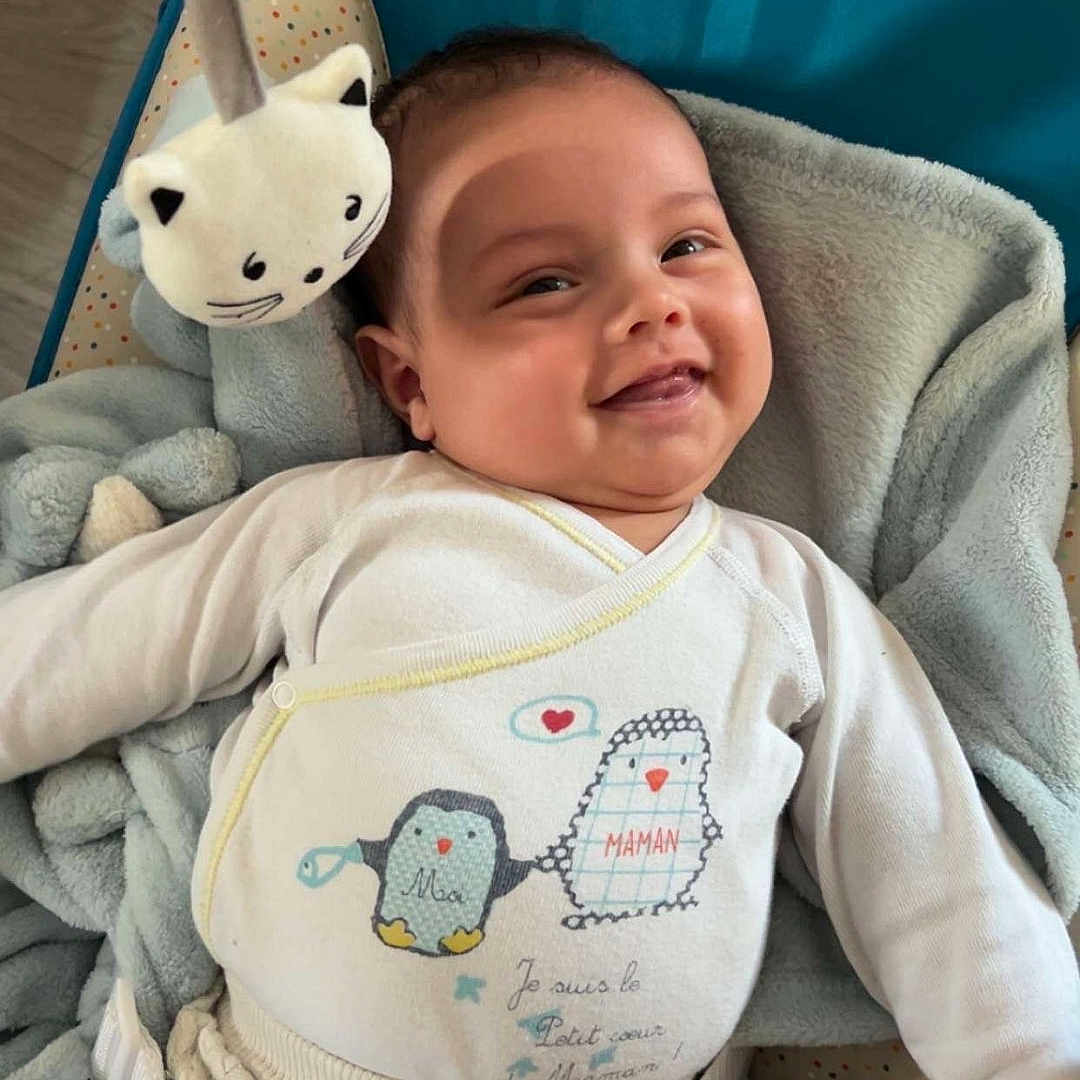 Diego participe au concours pour gagner de l'argent avec cette photo : baby, infant, smiling, baby_seat, toy, plush_toy, cat_toy, white_clothing, cushion, blanket, happy, face, cute, child, indoor, comfort, resting, baby_girl, cozy, portrait