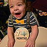 Luca joined the competition — help win amazing prizes! baby, child, smiling, high_chair, striped_shirt, bow_tie, suspenders, milestone, wooden_sign, 7_months, happy, indoor, cute, infant, person, portrait, hands, face, clothing, celebration
