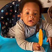 Jabari is registered to the contest to win money with this photo: baby, child, infant, walker, toy, orange, blue, face, curious, indoor, cushion, clothing, sweater, hand, seat, person, portrait, expression, furniture, home