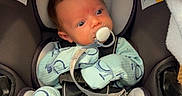 Anakin is registered to the contest to win money with this photo: baby, car_seat, pacifier, blue_onesie, mittens, blanket, infant, child, cute, newborn, seatbelt, sitting, indoor, soft_lighting, portrait, safety, young_child, cozy, comfort, head_support