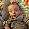 baby, infant, child, onesie, baby_seat, pacifier, cartoon, rainbow, elephant, monkey, indoor, cute, clothing, smiling, hand, person, face, toy, colorful, portrait