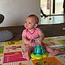 Luna joined the competition — help win amazing prizes! baby, child, pink_onesie, toy, play_mat, colorful, indoor, floor, carpet, person, punching_bag, curious, sitting, footwear, adult, home, living_room, window, light, furniture
