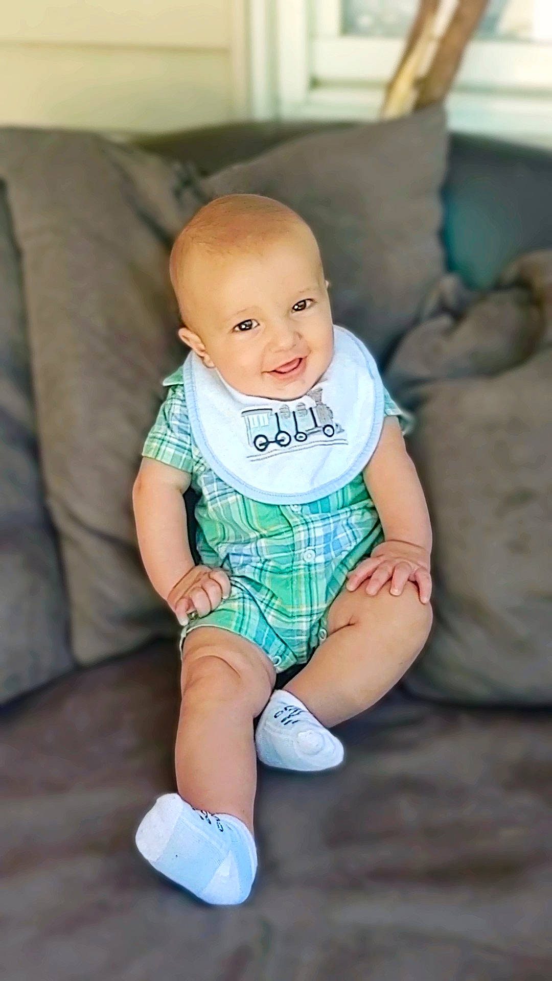 Lincoln is registered to the contest to win money with this photo: aqua, azure, baby, baby_toddler_clothing, cheek, comfort, couch, eye, face, happy, head, human_body, human_leg, iris, joy, knee, leg, person, sleeve, smile