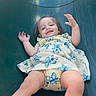 Lailah joined the competition — help win amazing prizes! toddler, child, baby, smiling, happy, playground, slide, sliding, outdoor, portrait, face, arms_raised, floral_dress, dress, play, recreation, joyful, sitting, blue_background, photograph
