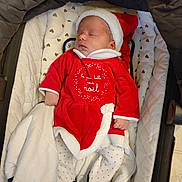 Romy a rejoint le concours — aidez-le/la à gagner de superbes lots ! baby, sleeping, infant, christmas_outfit, red_clothing, white_trim, hat, blanket, polka_dot, footwear, soft_toys, carrier, quilted, heart_pattern, cozy, cute, holiday, festive, newborn, indoors