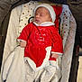 baby, sleeping, infant, christmas_outfit, red_clothing, white_trim, hat, blanket, polka_dot, footwear, soft_toys, carrier, quilted, heart_pattern, cozy, cute, holiday, festive, newborn, indoors