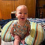 Charles is registered to the contest to win money with this photo: baby, smiling, indoor, pillow, bed, blanket, wood_paneling, onesie, child, happy, person, foot, face, furniture, cushion, cute, infant, sitting, home, cozy