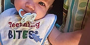 Charles joined the competition — help win amazing prizes! baby, infant, pacifier, bib, teething, smiling_crabs, clothing, patterned_cushion, colorful, cute, child, person, lying_down, blue, orange, white, face, eyes, soft_lighting, closeup