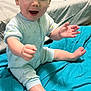 Charles is registered to the contest to win money with this photo: baby, child, infant, onesie, blue_blanket, sitting, happy, reaching, indoor, bed, wooden_furniture, smiling, cute, person, skin, foot, hand, head, expression, cozy