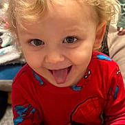 Samuel is registered to the contest to win money with this photo: child, toddler, curly_hair, blond_hair, red_clothing, spiderman, playful, tongue_out, indoor, person, cute, smiling, young_child, fun, happy, face, portrait, long_sleeve, clothing, expression
