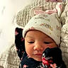 baby, infant, child, portrait, floral_outfit, knitted_hat, hat, sleeping, awake, face, smiling, bed, blanket, indoors, baby_clothing, floral_pattern, video_call, adult, photobomb, cozy