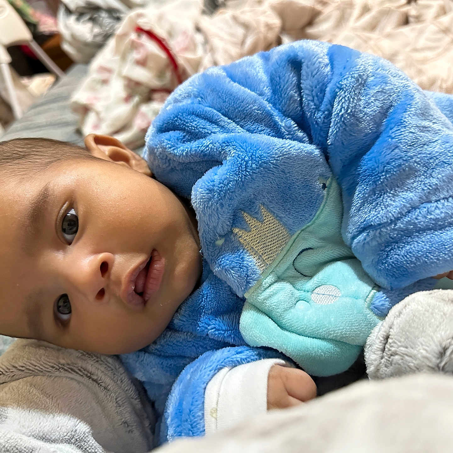 Aarin is registered to the contest to win money with this photo: baby, bed, blanket, blue_onesie, child, cozy, cushion, cute, eyes, face, hand, indoor, infant, mouth, newborn, person, portrait, sleepwear, soft_texture, warm