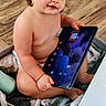 baby, basket, blanket, child, curious, curly_hair, cute, furniture, indoor, naked, person, play, sitting, skin, smile, tablet, technology, toddler, wood_floor, young_child