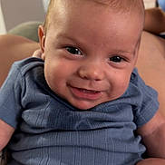 Weston is registered to the contest to win money with this photo: baby, smile, blue_onesie, infant, face, portrait, indoors, child, cute, happy, skin, person, sitting, young_child, expression, head, human, clothing, baby_girl, baby_boy