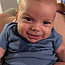 baby, smile, blue_onesie, infant, face, portrait, indoors, child, cute, happy, skin, person, sitting, young_child, expression, head, human, clothing, baby_girl, baby_boy