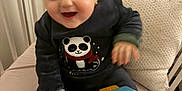 Jihane a rejoint le concours — aidez-le/la à gagner de superbes lots ! baby, child, panda_sweater, toy, crib, cushion, infant, playing, happy, smiling, indoor, furniture, person, clothing, hand, head, seat, blur, young_child, cute