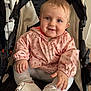 baby, child, smile, face, jacket, pink, floral, stroller, shoe, white_shoe, indoor, person, cute, happy, sitting, clothing, hand, legs, portrait, infant