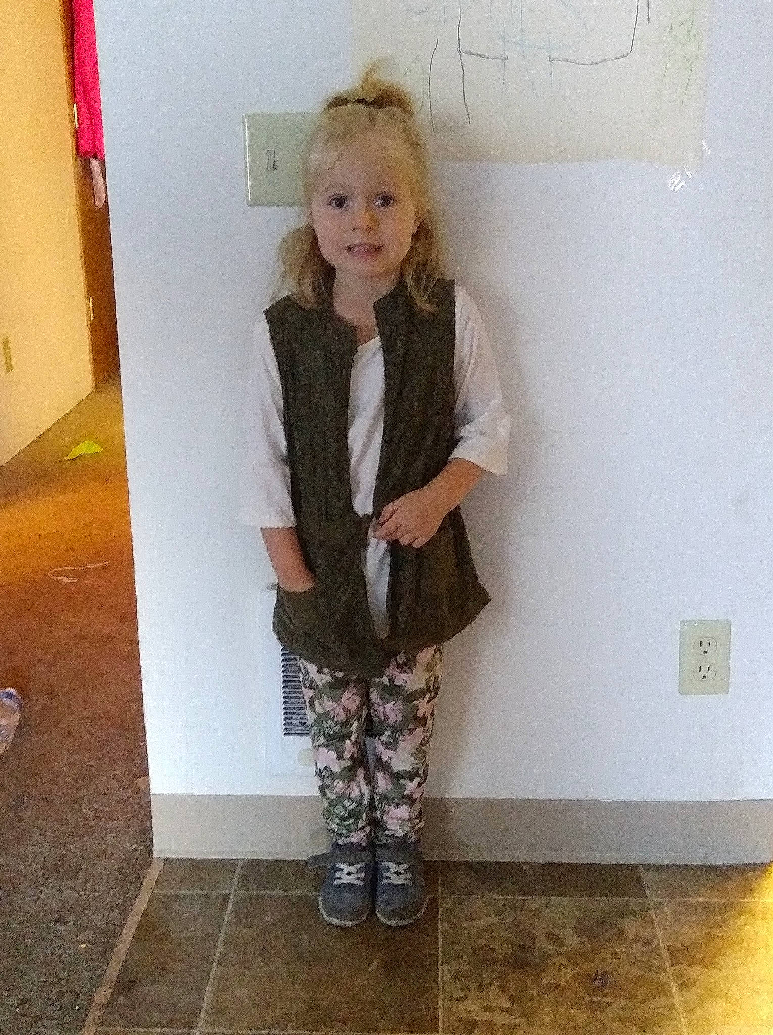 Makayla is registered to the contest to win money with this photo: child, clothing, footwear, jacket, khaki, knee, leg, outerwear, person, room, shoe, standing, trousers