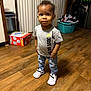 toddler, child, standing, indoors, wooden_floor, clothing, sneakers, jeans, tshirt, nike, laundry_basket, household, room, appliances, box, curtains, person, flooring, casual_wear, portrait