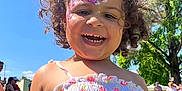 Layna a rejoint le concours — aidez-le/la à gagner de superbes lots ! child, girl, face_paint, curly_hair, smiling, outdoor, sunny, blue_sky, dress, people, trees, grass, summer, happy, portrait, daylight, park, event, cute, joyful