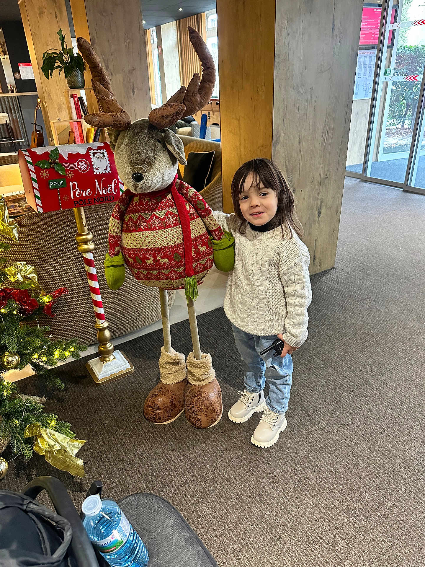 Baraa participe au concours pour gagner de l'argent avec cette photo : child, indoor, reindeer, holiday_decor, christmas_tree, decorations, sweater, jeans, boots, carpet, mailbox, furniture, plant, window, smile, person, holiday, festive, toy, light