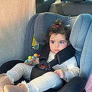 Mira participe au concours pour gagner de l'argent avec cette photo : backseat, boots, buckle, car_interior, car_seat, child, cozy, curly_hair, headrest, infant_clothing, little_hands, onesie, plush_toy, portrait, safety, seat_belt, serious_expression, toddler, toy, window